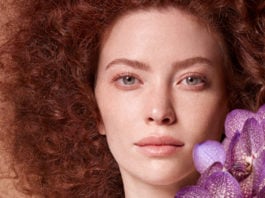 site-industries-cosmetiques 一位妇女手捧紫色兰花。