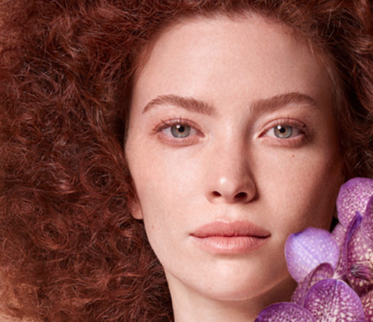 site-industries-cosmetiques Une femme tenant des orchidées violettes.