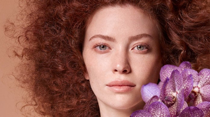 site-industries-cosmetiques A woman holding purple orchids.