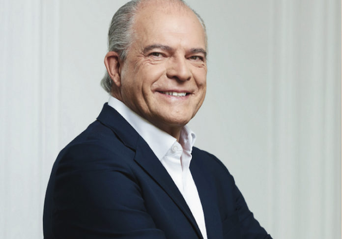site-industries-cosmetiques Un hombre trajeado sonríe a la cámara.