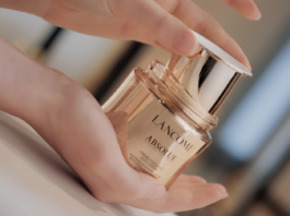 site-industries-cosmetiques 手拿金色化妆品瓶的女人。