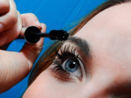 site-industries-cosmetiques Une femme se met du mascara sur les yeux.