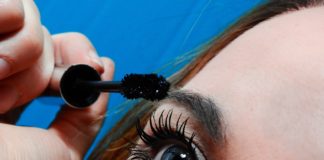 site-industries-cosmetiques Une femme se met du mascara sur les yeux.