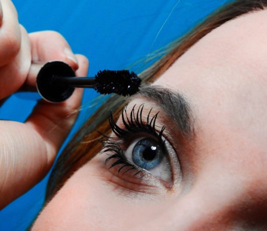 site-industries-cosmetiques Une femme se met du mascara sur les yeux.