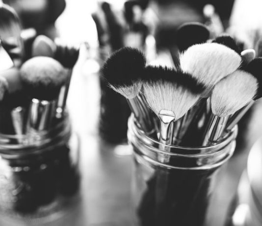 site-industries-cosmetiques Une photo monochrome de pinceaux de maquillage dans un récipient.