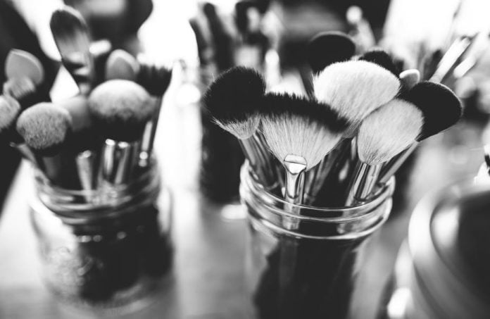 site-industries-cosmetiques Une photo monochrome de pinceaux de maquillage dans un récipient.