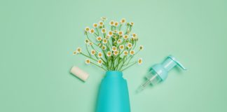 site-industries-cosmetiques Um vaso azul com flores e um frasco de sabão sobre um fundo verde, com a Cosmogen como parceiro.