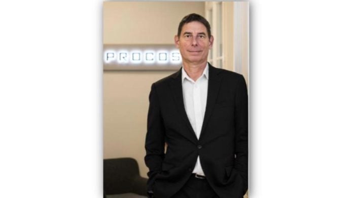 site-industries-cosmetiques Um homem de fato está em frente a uma parede Procos.