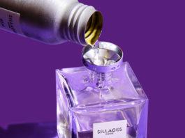 site-industries-cosmetiques Un flacon de parfum se déverse sur un fond violet orné du signe Stoelzle Masnières.