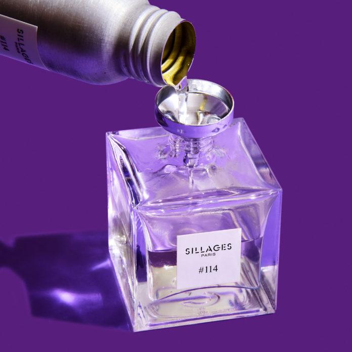 site-industries-cosmetiques Un flacon de parfum se déverse sur un fond violet orné du signe Stoelzle Masnières.