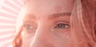 site-industries-cosmetiques Une femme avec un visage rayonnant portant un parfum rose valorisant.