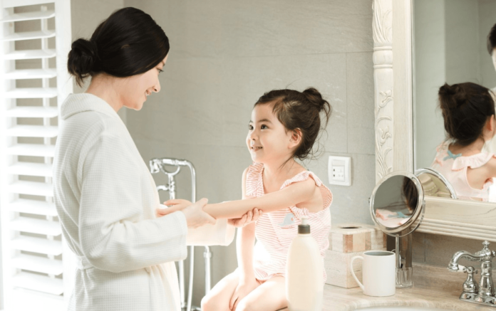 site-industries-cosmetiques A woman uses Zinc Oxide Micro from Croda Personal Care for a transparent sun protection formulation while washing her daughter's arm in the bathroom.