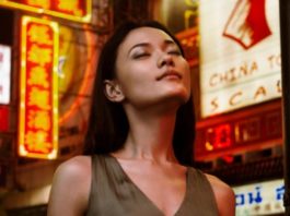 site-industries-cosmetiques Uma mulher em frente a um letreiro de néon num laboratório de inovação de perfumaria.