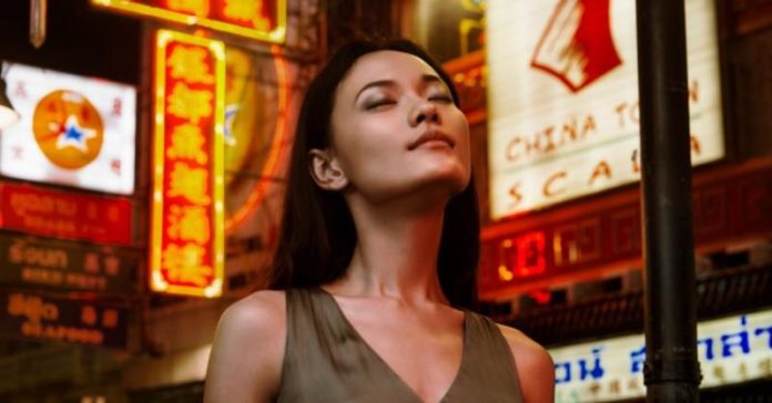 site-industries-cosmetiques A woman in front of a neon sign in a Perfumery innovation laboratory.