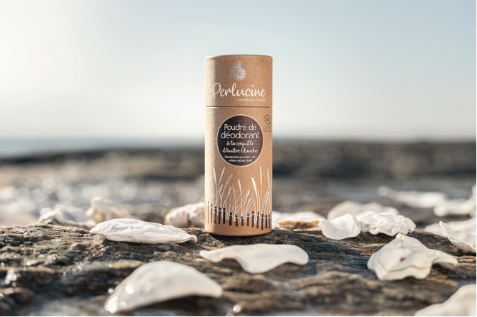 site-industries-cosmetiques Un tube de baume à lèvres posé sur un rocher à proximité de poudres cosmétiques.