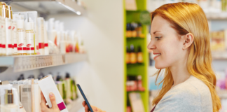 site-industries-cosmetiques A woman using a cell phone while shopping in a store.