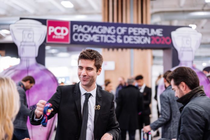 site-industries-cosmetiques A man displays a bottle of perfume at a trade show in Milan.