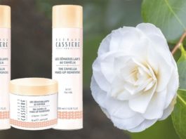 site-industries-cosmetiques A white flower with a bottle of camellia oil make-up remover next to it.