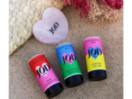 site-industries-cosmetiques Tres tubos de bálsamo labial descansan en una playa de arena.