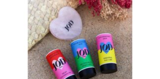 site-industries-cosmetiques Three tubes of lip balm resting on a sandy beach.