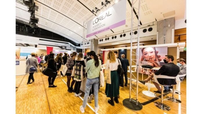 site-industries-cosmetiques Un groupe de personnes debout devant un kiosque, entouré d'affiches de brouillon.