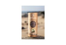 site-industries-cosmetiques Un tubo de bálsamo labial en una playa de arena.