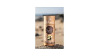 site-industries-cosmetiques Un tube de baume à lèvres posé sur une plage de sable.