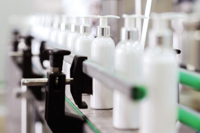 site-industries-cosmetiques Une ligne de bouteilles modernisées sur un tapis roulant dans une usine.