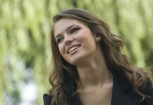 site-industries-cosmetiques Una joven posa feliz delante de un árbol.