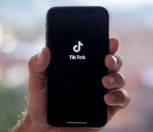 site-industries-cosmetiques Uma pessoa segurando um telemóvel com o logótipo tiktok.