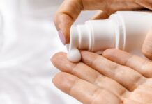 site-industries-cosmetiques A mão de uma mulher segura um frasco de creme cosmético.