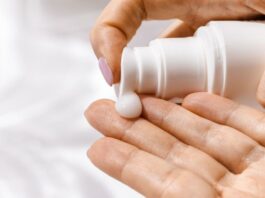 site-industries-cosmetiques A mão de uma mulher segura um frasco de creme cosmético.