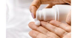 site-industries-cosmetiques A woman's hand holds a bottle of cosmetic cream.