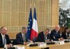 site-industries-cosmetiques Un comité assis à une table devant un drapeau.