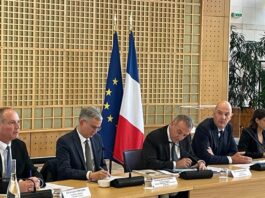 site-industries-cosmetiques Un comité assis à une table devant un drapeau.