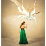 site-industries-cosmetiques A woman in a green dress under a white umbrella.