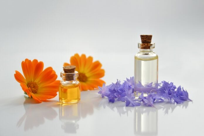 site-industries-cosmetiques Aceites esenciales y flores sobre una superficie blanca. El delicado aroma de estos aceites esenciales y los vibrantes colores de las flores crean un ambiente relajante en cualquier espacio. Ya sea para relajarse o como