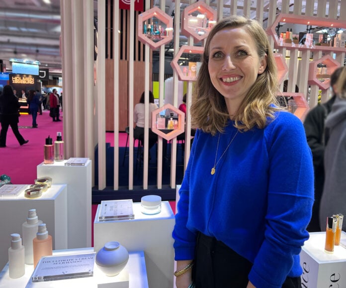 site-industries-cosmetiques Uma mulher está em frente a um expositor de cosméticos.