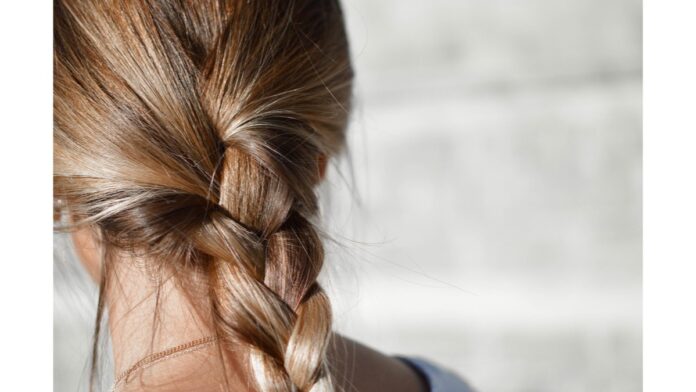 site-industries-cosmetiques Les cheveux d'une femme sont coiffés en queue de cheval tressée, soulignant la beauté de ses cheveux.