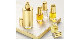 site-industries-cosmetiques A collection of luxury skincare products with golden accents on a marble-covered surface, featuring bottles of various sizes. This Innovation Awards 2025 finalist includes droppers and a spray bottle, featuring golden-yellow liquids sure to captivate at Paris Packaging Week.