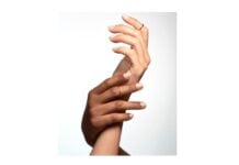 site-industries-cosmetiques Dos manos se entrelazan sobre un fondo blanco liso. Una es más oscura y la otra más clara, adornada con un anillo. Ambas llevan las uñas perfectamente cuidadas, tal vez pintadas con esmalte Fiabila para un acabado exquisito.