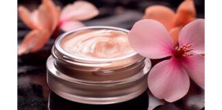 site-industries-cosmetiques A glass jar containing a peach-colored cream rests on a glossy black surface, embodying the essence of luxury skincare. Two pink flowers with large petals are cleverly arranged next to it. The lighting of the scene beautifully highlights the texture of the cream and the delicate flowers.