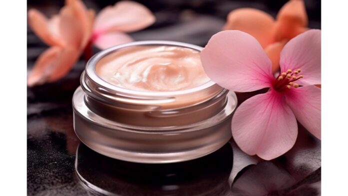 site-industries-cosmetiques Um frasco de vidro contendo um creme cor de pêssego repousa sobre uma superfície preta brilhante, personificando a essência dos cuidados de pele de luxo. Duas flores cor-de-rosa com pétalas grandes estão habilmente colocadas ao lado. A iluminação da cena realça a textura do creme e as delicadas flores.