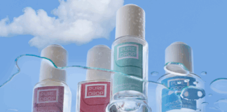 site-industries-cosmetiques Four bottles of Pure Drop nail polish in different colors stand out against a cloudy blue sky, dotted with water droplets and streaks. The image underlines the brand's commitment to responsible cosmetics packaging.