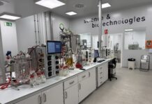 site-industries-cosmetiques Un laboratoire moderne équipé d'équipements et de machines scientifiques LipoTrue sur des paillasses blanches, de récipients en verre, de câbles et d'écrans. Le mur affiche « sciences et biotechnologies ». La pièce est propre, bien éclairée et axée sur la forte efficacité et les nouveaux ingrédients.