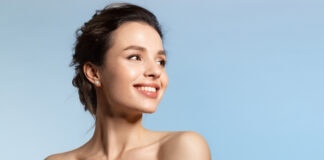site-industries-cosmetiques 一位黑发披肩、皮肤白皙的女性在浅蓝色的背景下侧身微笑。她的肩膀裸露在外，看起来很放松，就像在接受科学的健康评估。