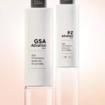 site-industries-cosmetiques Dos botellas rectangulares blancas con tapones de bomba negros se alzan sobre un fondo de suave degradado rosa. Las botellas llevan las etiquetas "GSA Advance" y "PZ Advance", con diseños de Aptar, y ambas indican un alto rendimiento y una reciclabilidad avanzada.