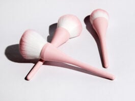 site-industries-cosmetiques Três pincéis de maquilhagem com cabos cor-de-rosa e cerdas brancas e cor-de-rosa estão dispostos numa superfície branca, lançando sombras suaves - uma configuração perfeita para a sua próxima rotina de beleza Brouillon auto.