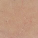 site-industries-cosmetiques Imagem de grande plano de pele humana com rídulas visíveis, poros e alguns pêlos esparsos. O tom de pele é claro, com ligeira vermelhidão e uma textura natural que se assemelha a um efeito de auto-escurecimento.