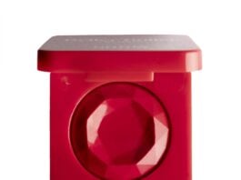 site-industries-cosmetiques Polvera roja de forma cuadrada con un producto de maquillaje rojo facetado en su interior, similar a una piedra preciosa. La tapa está parcialmente abierta y la polvera aparece fotografiada sobre un fondo blanco.
